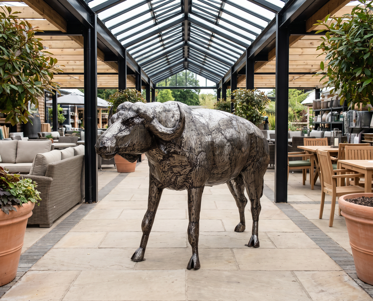 Handcrafted welded-steel buffalo sculpture displayed in an outdoor-living showroom.