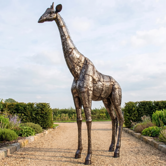 Handcrafted welded-steel giraffe sculpture in a landscaped garden.