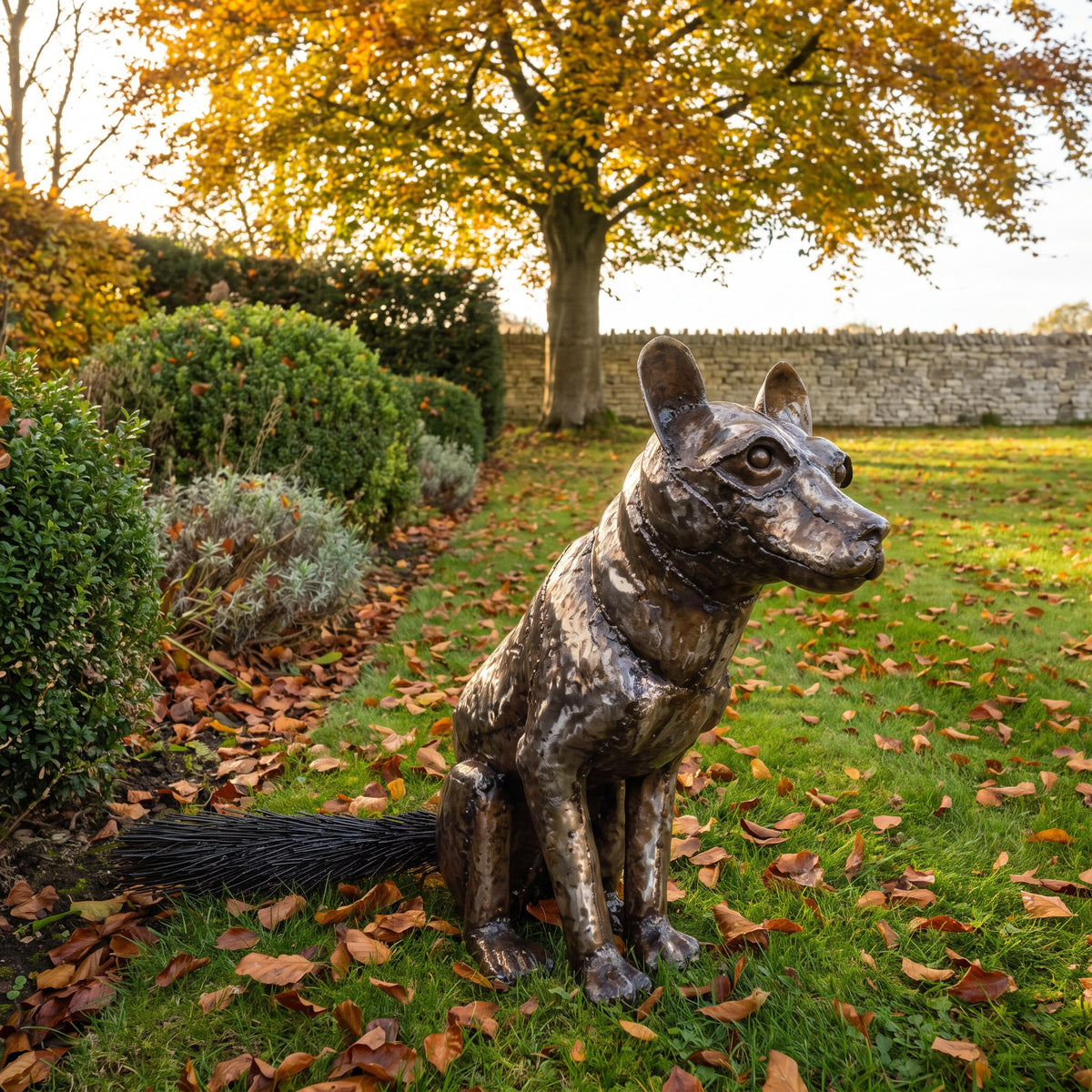 Sitting Fox metal sculpture beside an autumn garden path